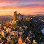 Najac (Aveyron) : village perché dominé par un château médiéval surplombant la rivière au coucher du soleil.